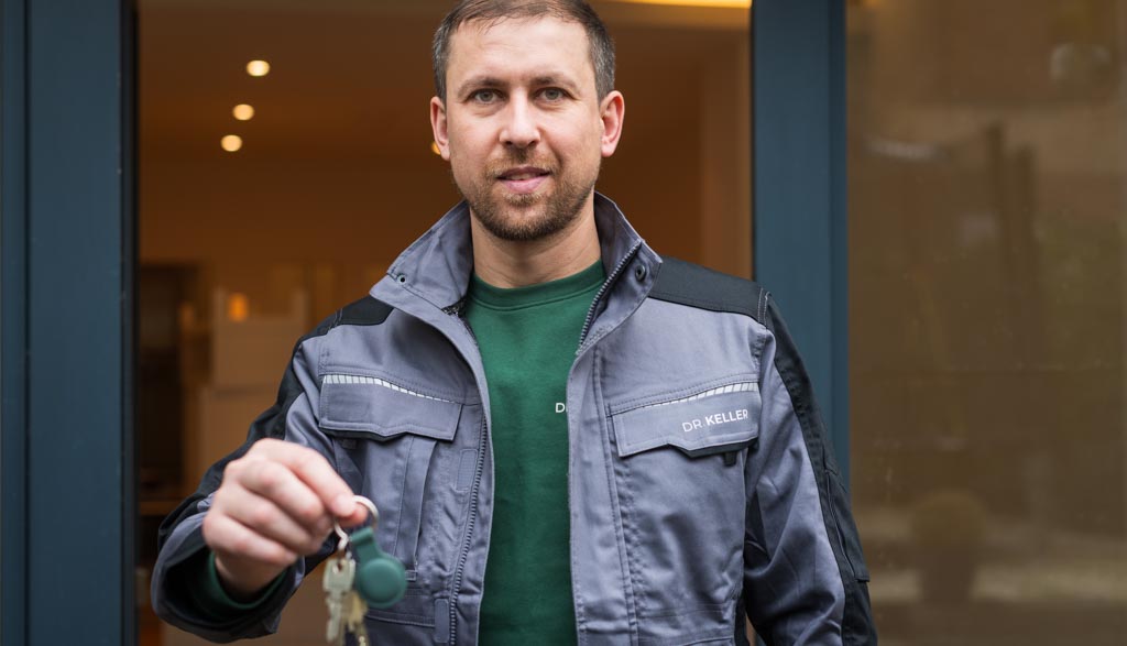 handwerker-mit-schluesselbund-dr-keller-logo-2 Nahaufnahme eines Handwerkers in einer Jacke mit 'DR. KELLER'-Logo, der einen Schlüsselbund hält, bereit, ein neues Projekt zu abzuschließen.
