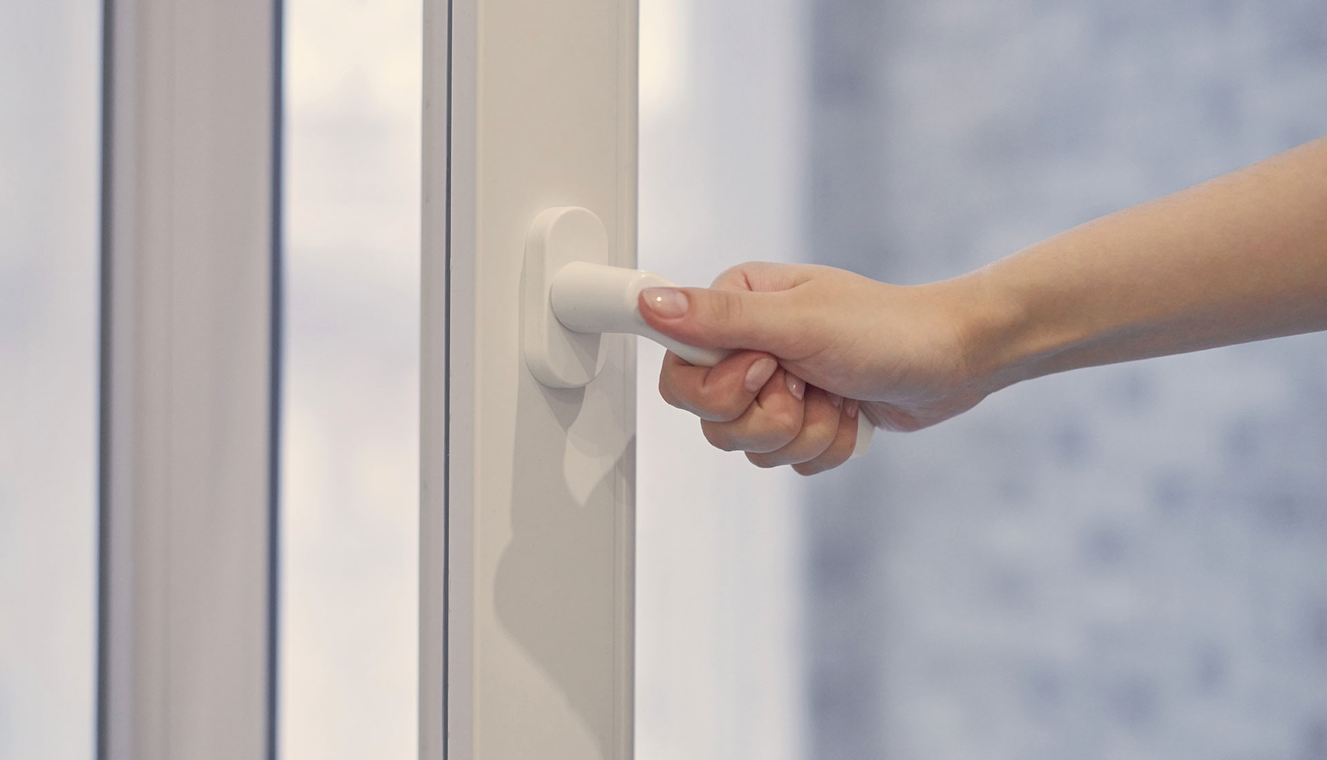 effektives-lueften-durch-tuer-oeffnen-heizen Hand einer Person, die einen weißen Türgriff hält und eine Tür öffnet, symbolisiert die Bedeutung des Lüftens für die Raumluftqualität.